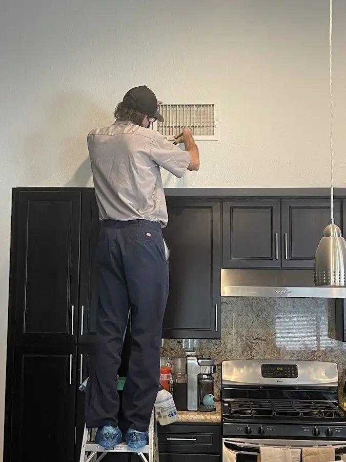 Technician inspecting an air vent during HVAC service in West Deer